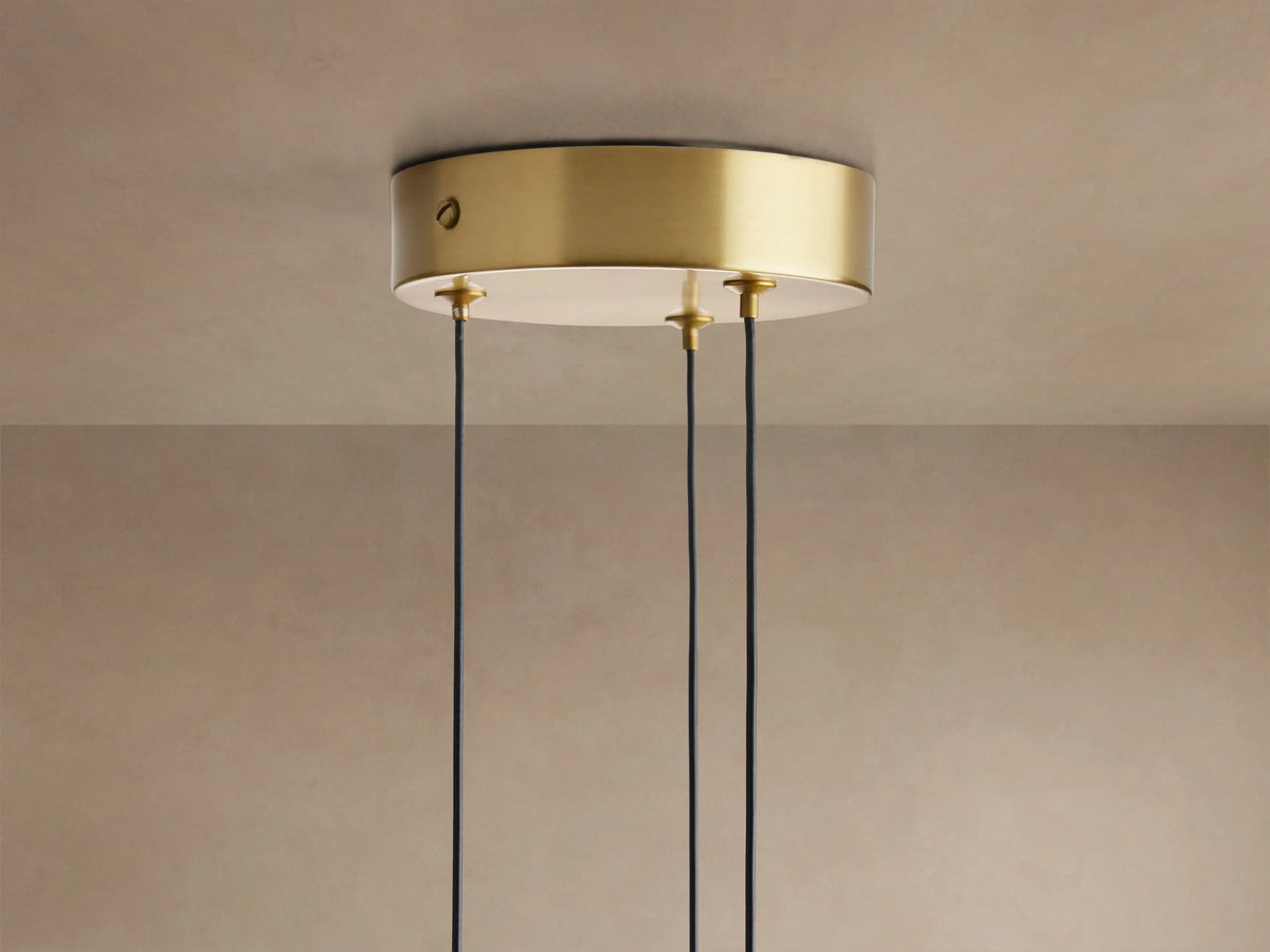 Three Soltaire Cluster Pendants with brass tops, clear bubble-filled glass teardrop shades illuminated against a neutral wall.