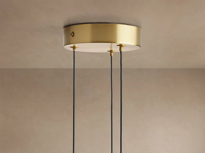 Three Soltaire Cluster Pendants with brass tops, clear bubble-filled glass teardrop shades illuminated against a neutral wall.