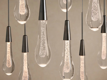Soltaire Linear Chandelier: A close-up of multiple clear, tear-drop glass lights with sparkling internal LEDs and dark tapered caps.