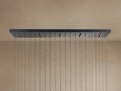 Soltaire Linear Chandelier with a dark rectangular canopy mounted to a light brown surface, featuring many thin hanging wires.