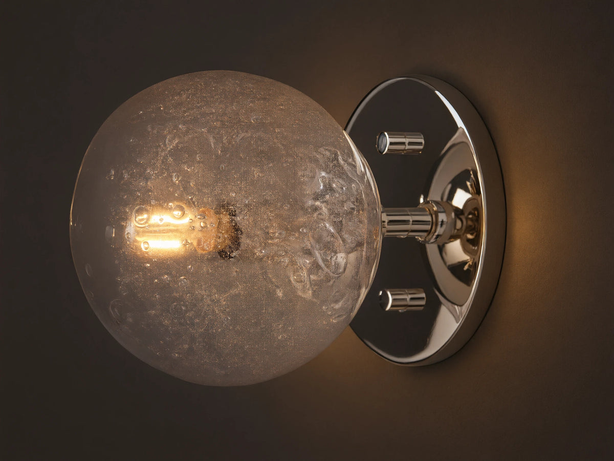 Mandoza Sconce with polished nickel-finished steel base featuring a textured hand-blown glass globe, mounted on a wall.