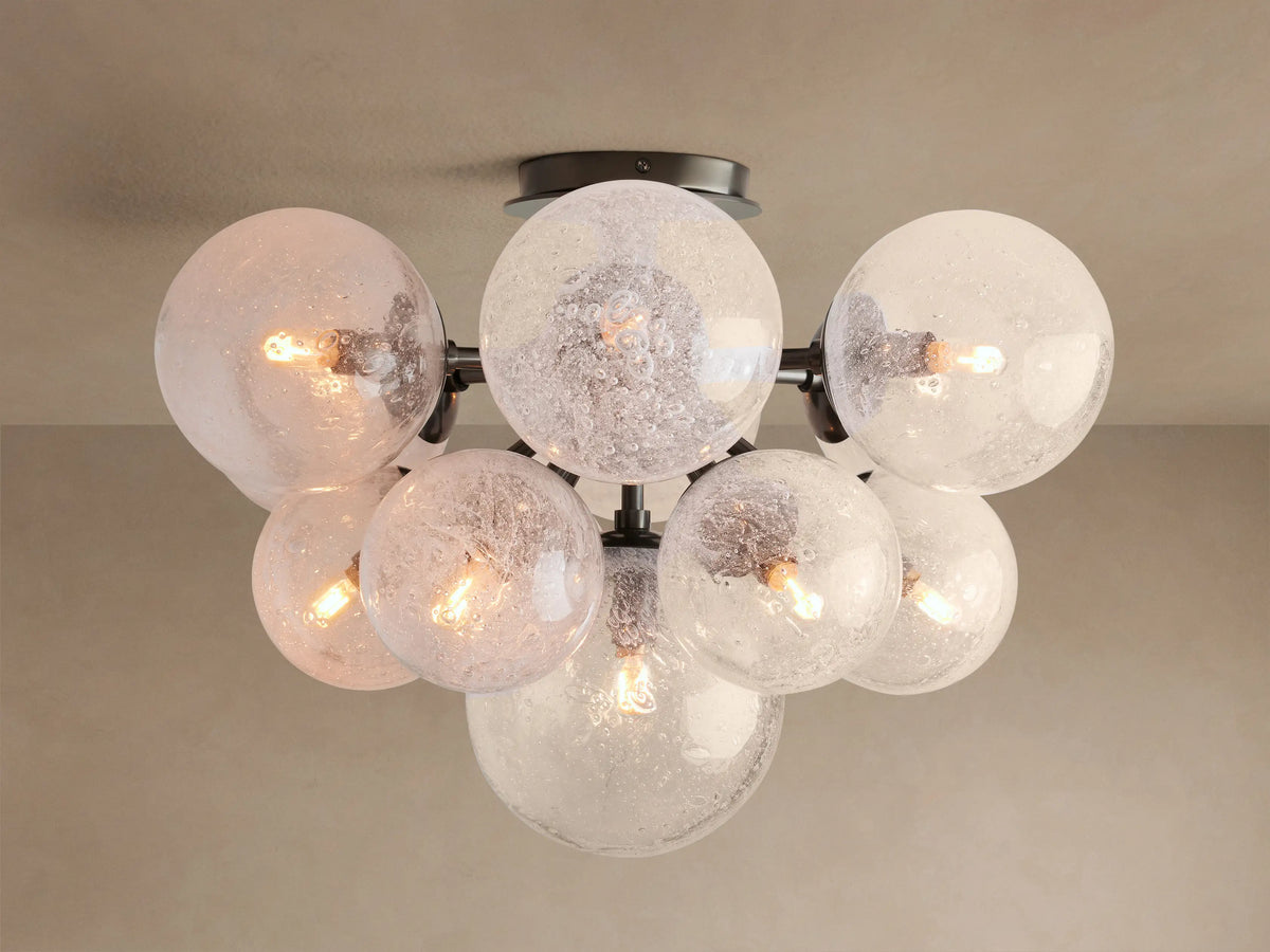 Mandoza Flush Mount with multiple clear, bubbled hand-blown glass globes on a dark metal frame, illuminated.