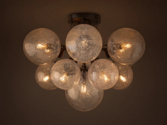 Mandoza Flush Mount with multiple clear, bubbled hand-blown glass globes on a dark metal frame, illuminated.