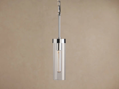 Andreas Pendant, polished nickel with clear cylindrical glass shade and vintage-style filament bulb, hanging from chain and rod against brown.