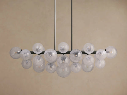 Mandoza Linear Chandelier with a burnished brass frame holding multiple illuminated, speckled hand-blown glass globes.