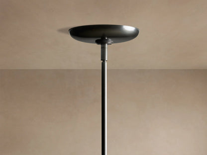 Close-up of Etoile Chandelier, showing three illuminated brass and bronze shades on dark grey arms, glowing on beige background.