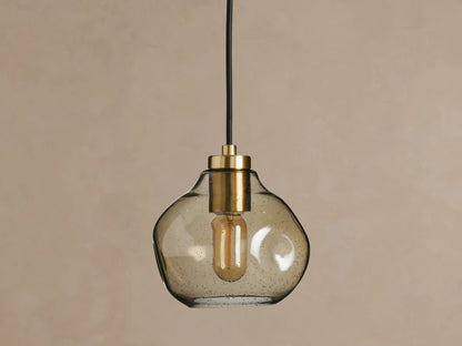 Organic 8" Pendant with a unique, smoky mouth-blown glass shade, brass fitting, black fabric cord, and glowing filament bulb.
