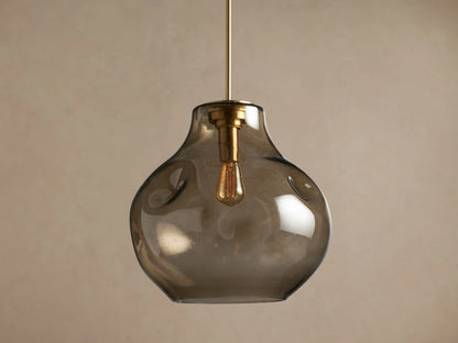 Organic 16" Pendant: Irregular, smoky, seeded glass shade with brass hardware, housing a glowing filament bulb, hanging.