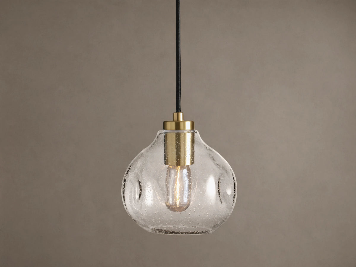 Organic 8" Pendant: Clear, seeded mouth-blown glass shade with brass hardware, black cord, and a glowing Edison bulb.