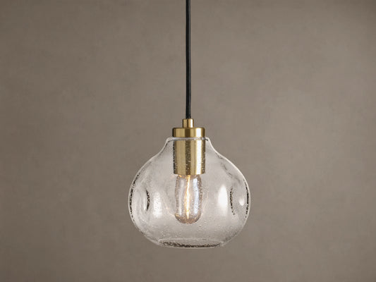 Organic 8" Pendant: Clear, seeded mouth-blown glass shade with brass hardware, black cord, and a glowing Edison bulb.