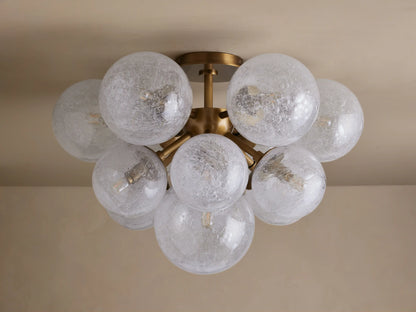Mandoza Flush Mount, burnished brass base with multiple glowing, textured glass globes clustered on a light ceiling.