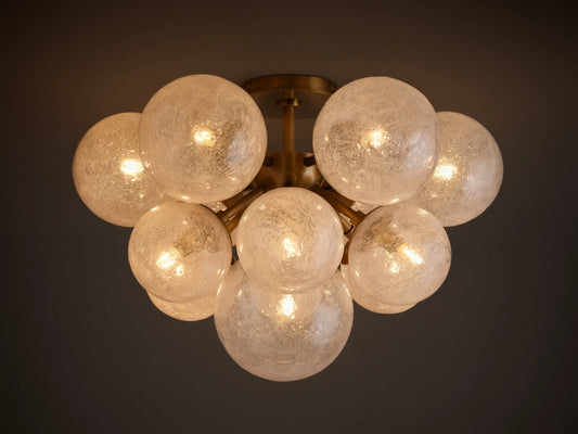Mandoza Flush Mount, burnished brass base with multiple glowing, textured glass globes clustered on a light ceiling.