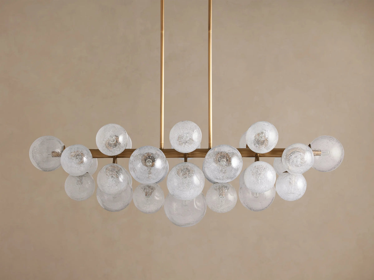 Mandoza Linear Chandelier with a horizontal brass-toned frame holding many illuminated, spherical, frosted glass globes.