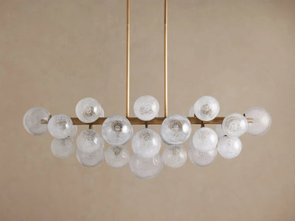 Mandoza Linear Chandelier with a horizontal brass-toned frame holding many illuminated, spherical, frosted glass globes.
