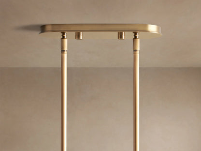 Mandoza Linear Chandelier: Close-up of clear, bubble-filled glass globes emitting warm light, connected by burnished brass metal.