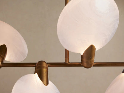 Lyla Linear Chandelier with a horizontal brass frame holding 8 milky white hand-blown glass shades, suspended by two rods.
