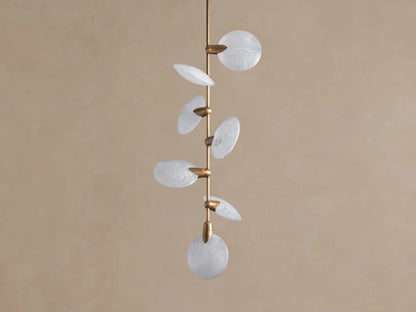 Lyla Pendant: 7 round, swirled hand-blown glass shades with glowing LED lights on a vertical brass stem against a brown wall.