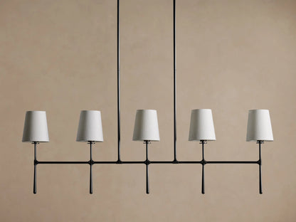 Rhodes Linear Chandelier with 5 tapered light linen shades on a dark metal horizontal bar, hanging from two rods.