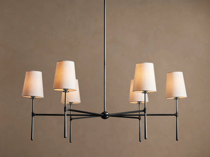 Rhodes Round Chandelier, dark metal frame with six lit tapered linen shades, centered against a warm brown wall.