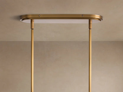 Close-up of a Rhodes Linear Chandelier showing two white tapered linen shades on a burnished brass metal frame.