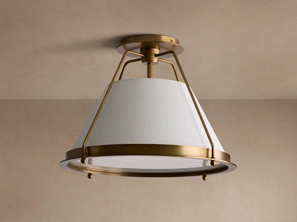 Burnished brass Shelton Flush Mount light, tapered off-white linen shade diffusing a warm glow, mounted to a light ceiling.