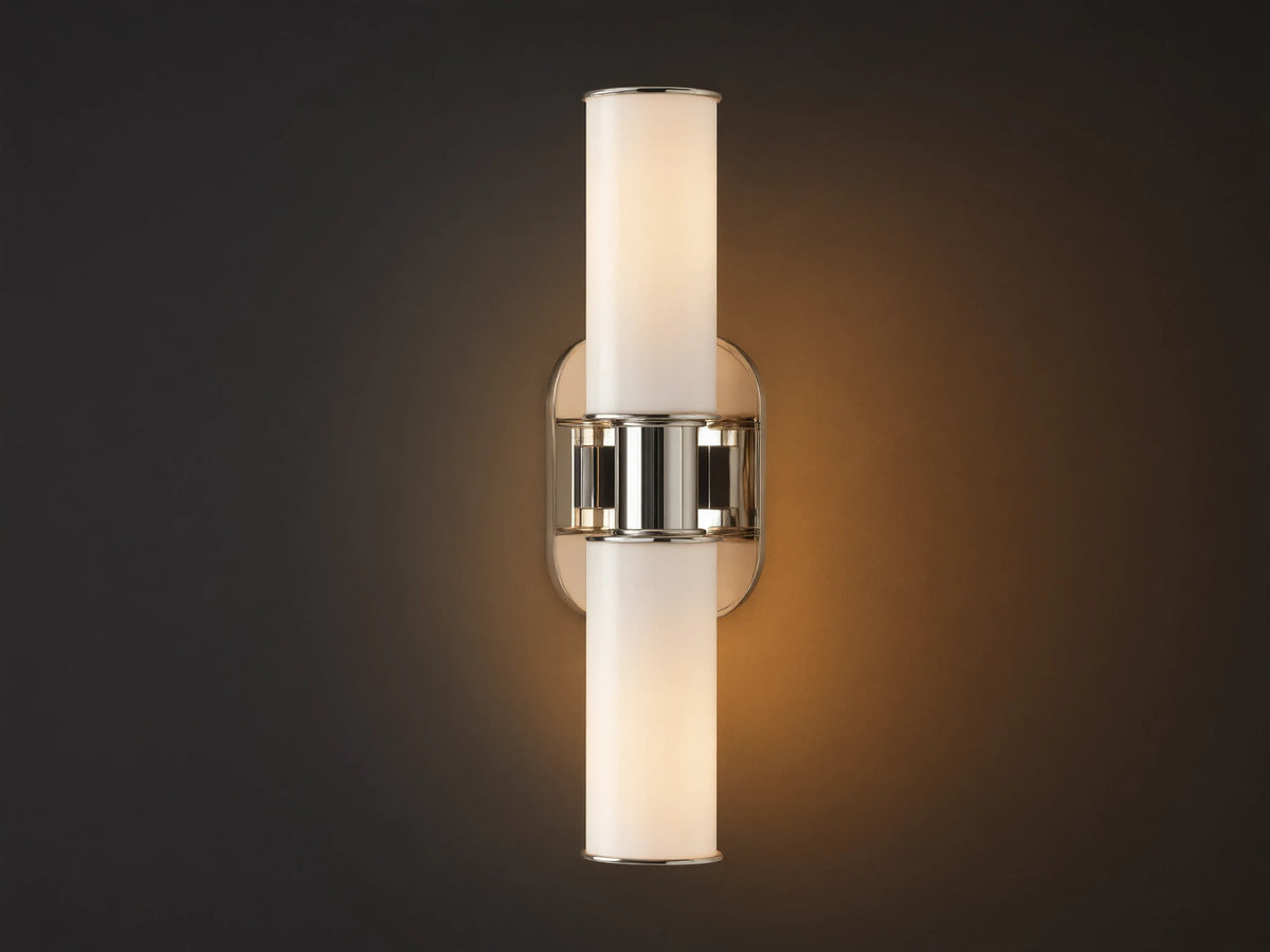 Harlin Double Sconce with two glowing vertical milk glass shades and polished nickel accents, mounted on a textured brown wall.