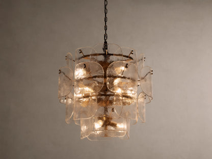 Blaire Round Chandelier with layered, curved clear glass panels creating a textured effect. Lit with warm light, hung by a brass-finished chain.