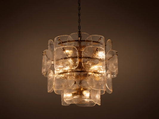 Blaire Round Chandelier with layered, curved clear glass panels creating a textured effect. Lit with warm light, hung by a brass-finished chain.