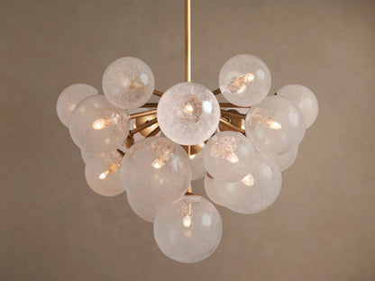 Mandoza Chandelier: Burnished brass frame holds numerous textured glass globes, each illuminated with warm light.