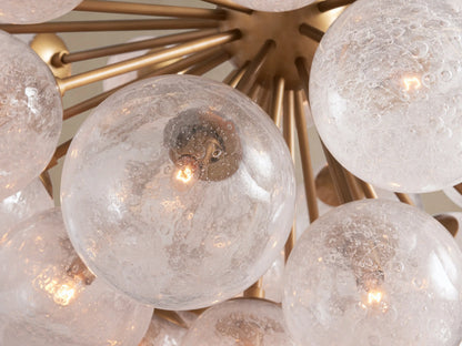 Mandoza Chandelier, a modern starburst-style fixture with burnished brass arms and numerous textured, clear glass globes.