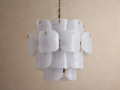 Blaire Round Chandelier with layered, curved white pearlescent glass panels and brass accents, hanging against a light wall.