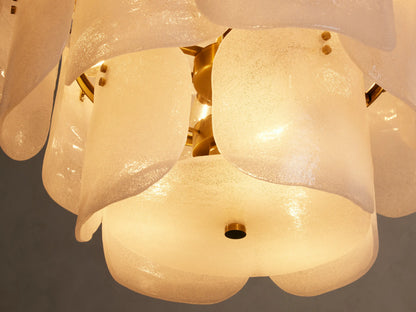 Close-up of Blaire Round Chandelier with curved, pearlescent white glass panels, bubbly texture, and warm glow. Brass accents.
