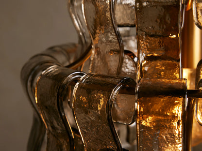Ghiaccio Pendant with curved glass and steel frame, showing a tiered, wave-like design. Hangs from a gold rod and chain.