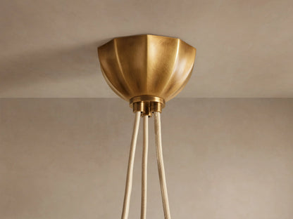 Agnes Chandelier: Three cream paneled glass globes glowing, suspended by antique brass hardware in a draped arrangement.