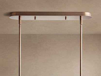 Close-up of Daphne Fabric Linear Chandelier with three cylindrical cream parchment shades, dark brown trim, and bronze linear frame, viewed from below.