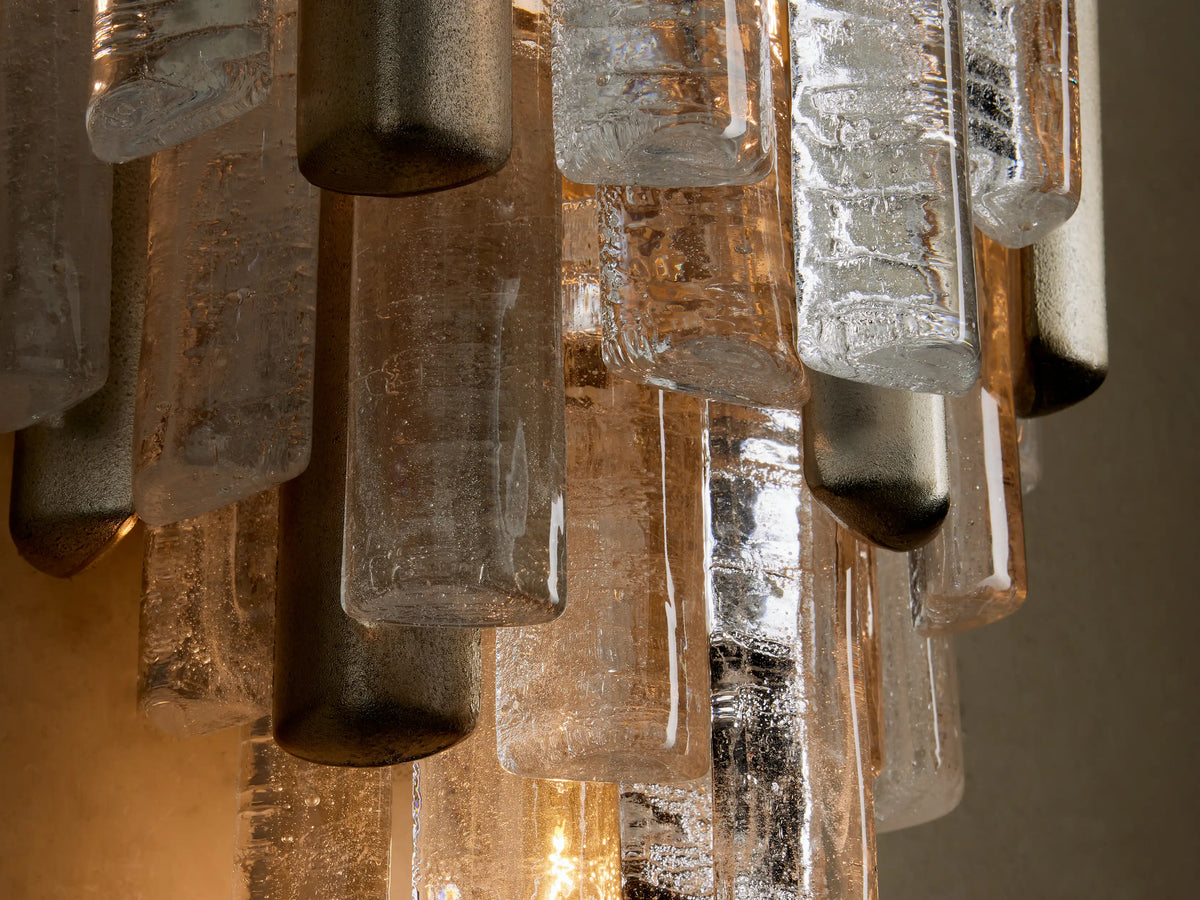 Neve Sconce: Tiered clear & textured cast glass rectangles with champagne aluminum accents on a light beige wall.