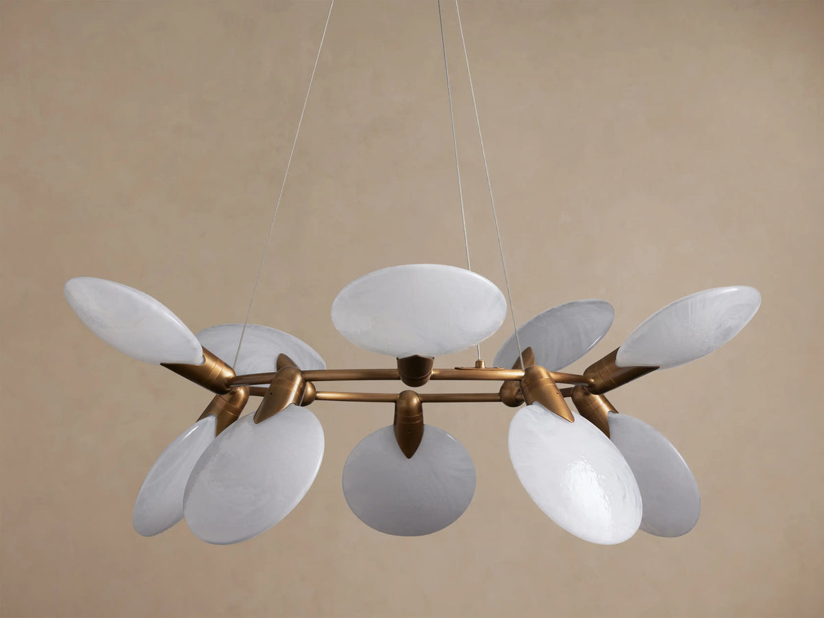 Lyla Round Chandelier with a circular brass-plated frame, featuring 10 glowing, oval hand-blown white glass shades, hanging.