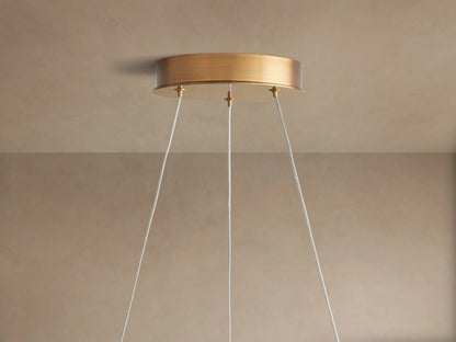 Angled close-up of Lyla Round Chandelier, showing frosted white glass shades with swirls and a textured brass frame.