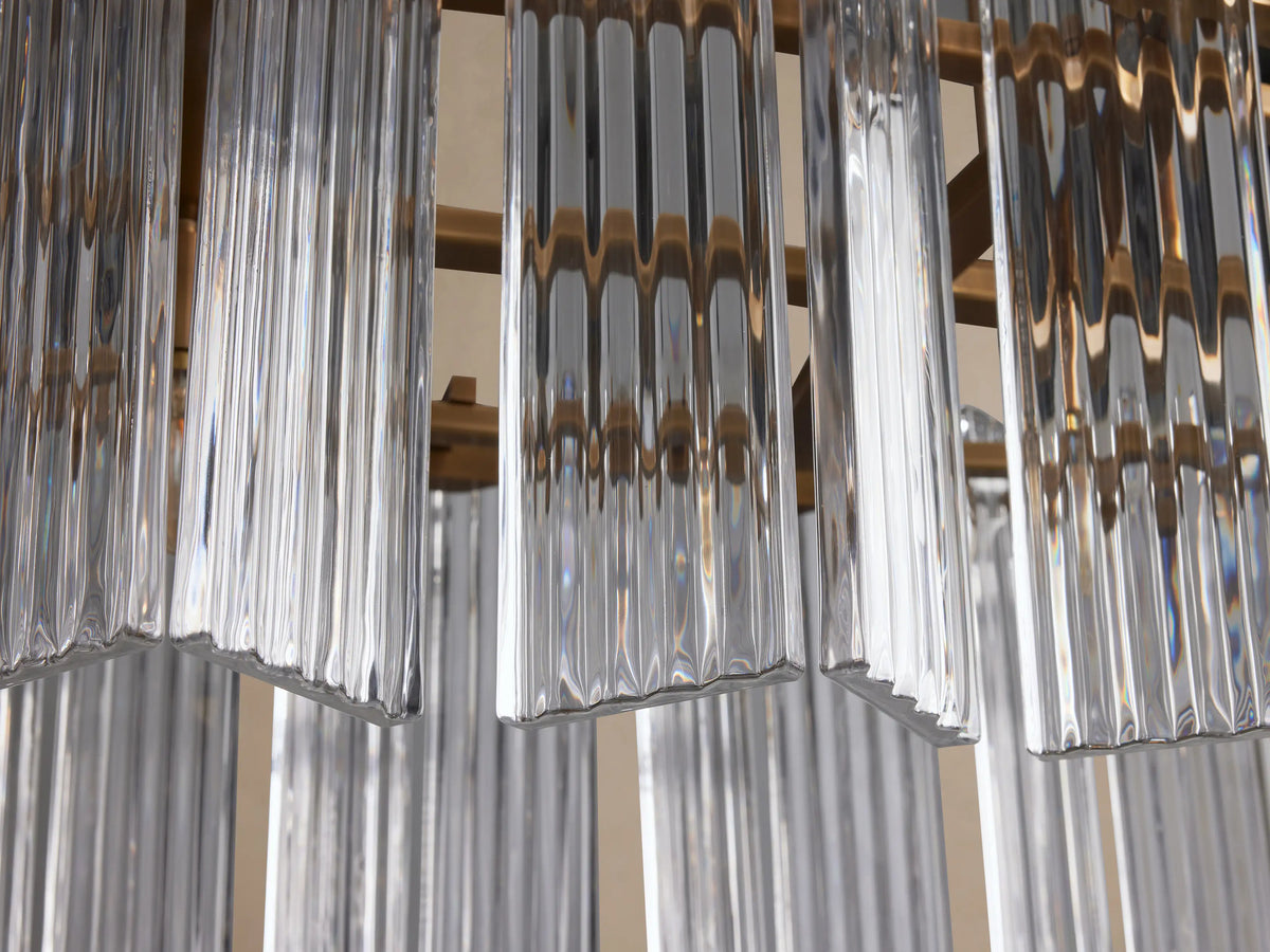 Close-up of Delsie Oval Chandelier with clear, vertically fluted glass panels and burnished brass framework.
