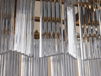 Close-up of Delsie Oval Chandelier with clear, vertically fluted glass panels and burnished brass framework.