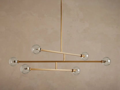 Front view of modern chandelier with illuminated clear glass ribbed globes and brass-toned metal arms.