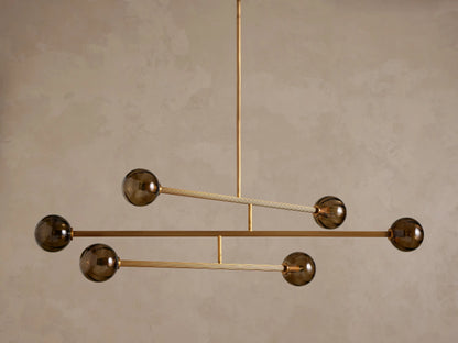 Modern chandelier with a brass frame and five smoky brown glass globe shades, suspended from above.