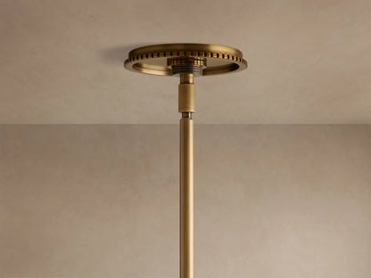 Three-light brass and clear glass pendant fixture with exposed filament bulbs glowing, suspended from a rod.