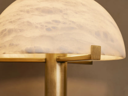 Emerie Table Lamp with a dome-shaped alabaster shade and brass base, featuring a close-up of textured stone and metal details.