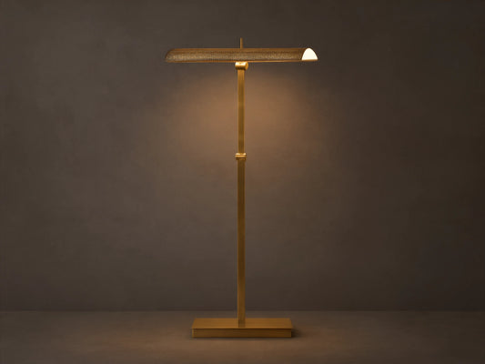 Abel Metal Floor Lamp: Upright, brass finish, rectangular base, long perforated shade emitting warm LED light. Beige wall, wood floor.