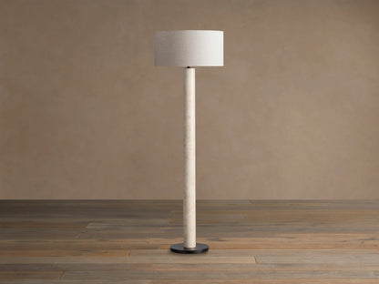 Brixton Floor Lamp, tall and slender, with a natural cream marble post, black circular base, and light beige fabric drum shade.