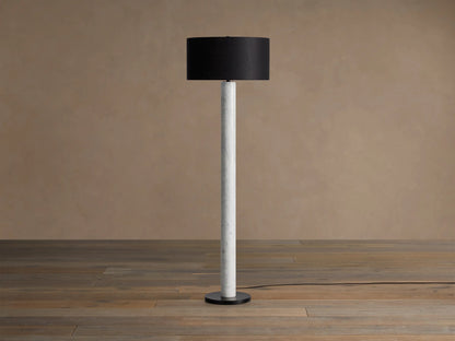 Brixton Floor Lamp with a white marble column, dark fabric drum shade, and black steel base, standing on a wooden floor.