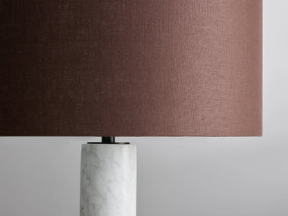 Brixton Floor Lamp with brown cylindrical shade, white marble column, black circular base, on wooden floor against neutral wall.
