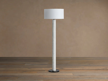 Brixton Floor Lamp: Tall white marble column, white cylindrical fabric shade, round black base. On wooden floor.