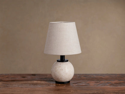 Celia Outdoor Rechargeable Lamp on rustic wood table. Cream marble base, matte black accents, lighted flax linen shade.